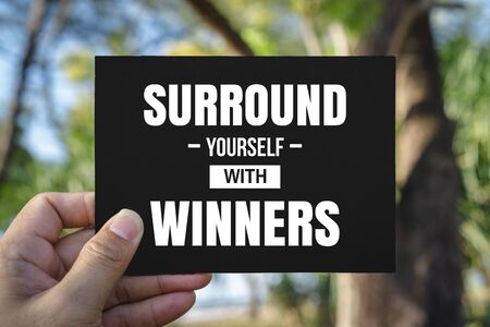 Inspirational and Motivational Quote. Hand Holding Black Paper. Surround Yourself With Winners.の写真素材