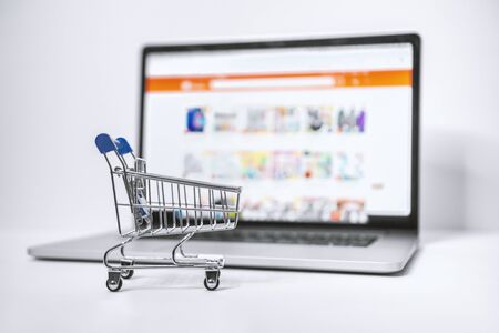 E-Shopping Concept. Shopping Cart and Laptop. Shopping Cart on Blue Background.の写真素材