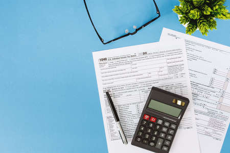 Tax Form 1040 and Calculator on Light Blue Backgroundの写真素材