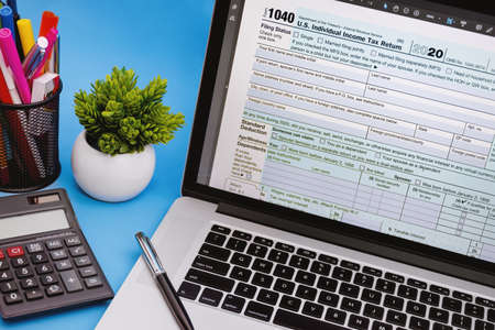 Tax Form 1040 on Laptop Screen on Light Blue Background