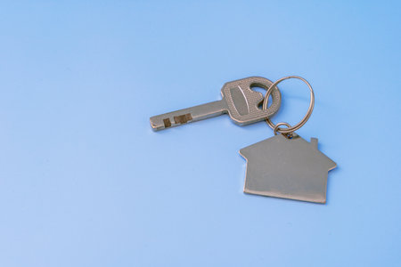 Key With House Shaped Key Chain on Blue Backgroundの写真素材