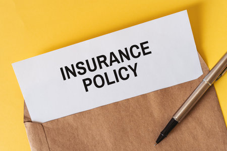 "Insurance Policy Document in Envelope" - A white paper insurance policy document inside an envelope with a pen.の写真素材