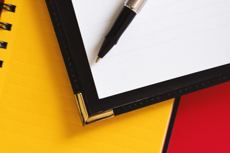 "Personal Planner and Pen on Notebook" - A personal planner and pen on a notebook with a red background.の写真素材