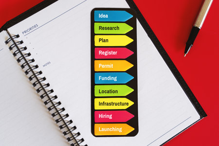 "Colorful Sticky Notes for Business" - Colorful sticky notes on a red background with a diary book and pen for essential business steps.の写真素材