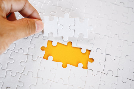 Hand Putting The Last Pieces To Solve Jigsaw Puzzleの写真素材