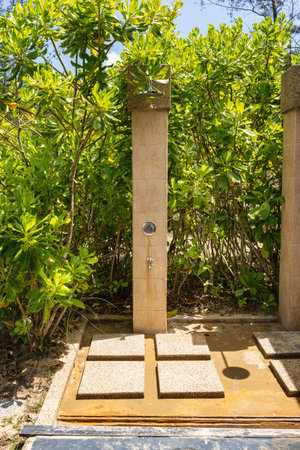 Outdoor shower facility with stone tiles and lush greenery.の写真素材