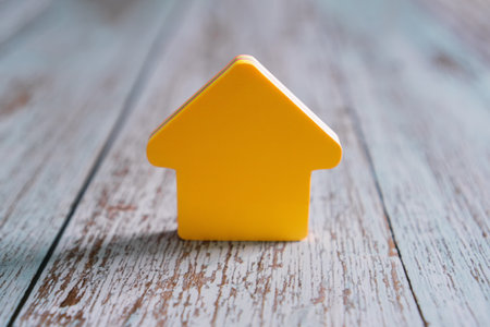 Bright yellow house icon on rustic wooden background - home concept.の写真素材