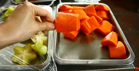 Hand picks a piece of papayaの写真素材