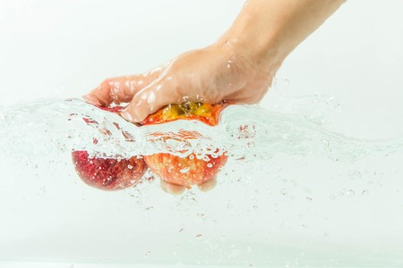 hand and two apples in waterの写真素材
