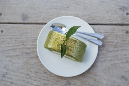 creamy green tea roll with fresh green leaves on white plateの写真素材