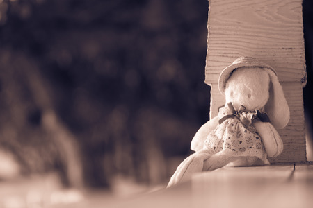 Cute rabbit doll sit on the wood bench, lonely feeling with warm toneの写真素材
