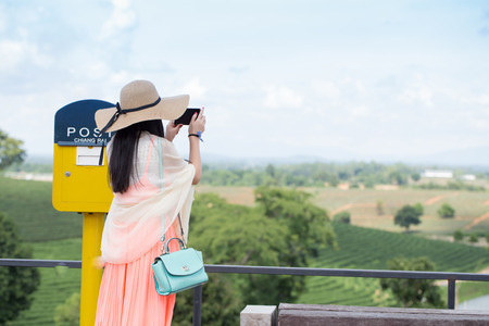 Beautiful woman with hat and nice dress shooting photo of landscape in cold tone as film toneの写真素材