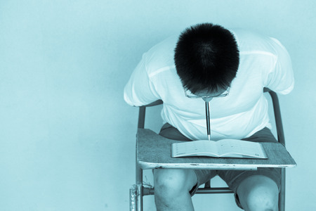 Handicap sitting Asian man having book on orange wallの写真素材