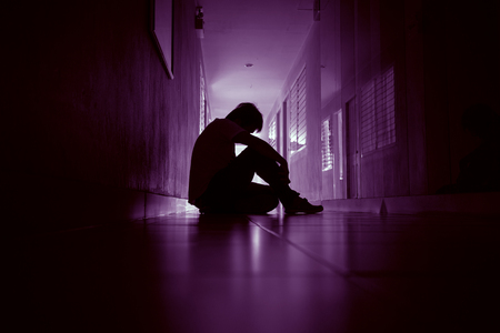 Silhouette of adult man in walkway of condominium or office, low key tone and dark with sad moodの写真素材