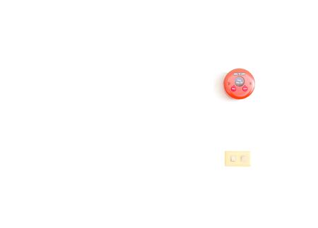 Round red alarm fire with old white light switch on white wall