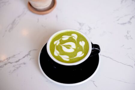 Green tea latter art, Matcha japanese with white whipped cream in black cup. Hot green tea beverage...