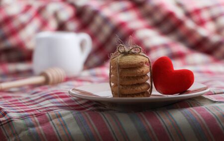 Round sweet cookies. Delicious dessert with high sugar and carbohydrate suitable for eating with milk and tea or coffee on color and white background with colorful placemat with red heart for Saint Valentine's Dayの写真素材