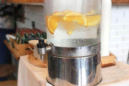 Orange infusion in cold water and ice in big tank for fresh and cool water. Good beverage and healthy drink. Infusion lemonadeの写真素材