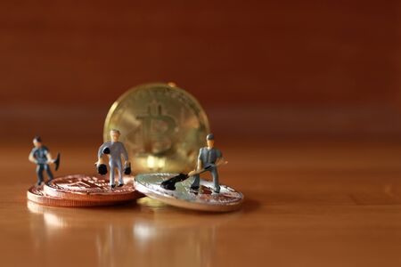 Engineering worker digging and working with coin as business and indurstry concept. Figure or miniature with gold, silver, bronze coin as work hard for money ideaの写真素材