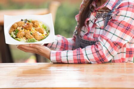 Asian woman enjoying her healthy salad with crispy salad in big white bowl on the table outdoor in gardenの写真素材