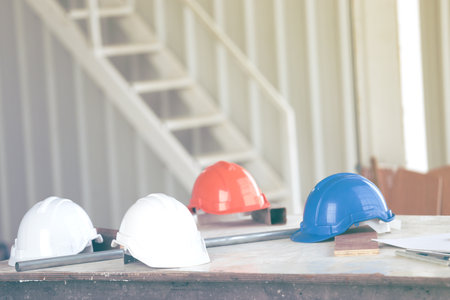 Safety helmet and hard hat on wood table in construction site with copy space.
