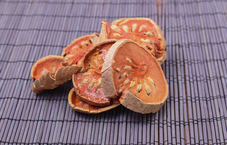 Dried quince on bamboo table. Bengal Quince or comman name is  Bael fruit, Bilak and Elephant's Apple to make Bael Fruit Herbal drink in hot water as tea or boiling.の写真素材