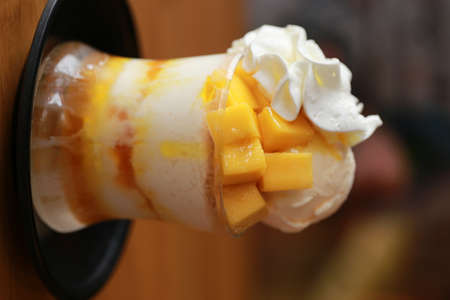 Sweet yellow mango bingsu, modern korean cold dessert or korean ice cream in glass. Tasty and famous summer sweet.の写真素材