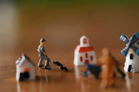 Small house, tiny windmill, little tower as miniature hometown as villate toy on wood floor in concept of living and working underconstruction with workerの写真素材