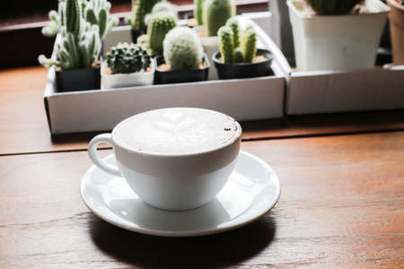 Latte art hot coffee with tulip milk latte art on top of white ceramic glass set on wood table in coffee shopの写真素材
