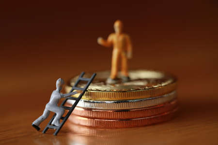 Engineering worker digging and working with coin as business and indurstry concept. Figure or miniature with gold, silver, bronze coin as work hard for money ideaの写真素材