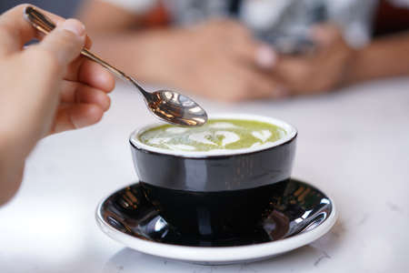 Green tea latter art, Matcha japanese with white whipped cream in black cup. Hot green tea beverage with heart latte milk art in coffee shopの写真素材