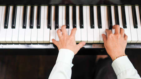 Adult woman plays electronic piano with note sheet. Professional pianist showing solo on acoustic...