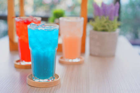 Refreshing cold beverage for summer on ice. Colorful summer drink in tall glass with wood saucer for hot day and party.の写真素材