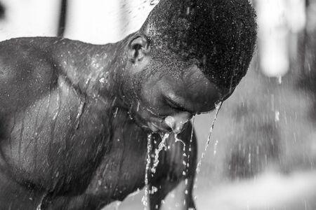 Photo shoot for a black handsome guy, water runs down the face and bodyの写真素材