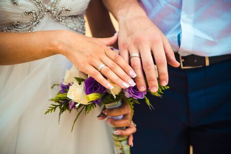 Hands and rings on wedding bouquet on the beachの写真素材