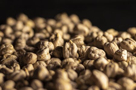 close-up studio shot with selective focus of yellow chickpeas in black backgroundの写真素材