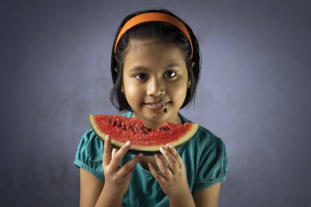 an Indian girl child eating water melon with smiling faceの写真素材