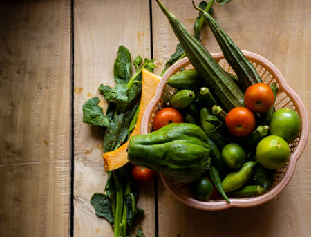 Top view of a plastic basket full of Indian fresh vegetables on wooden surfaceの写真素材