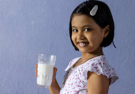 Cute little Indian / asian girl showing muscles after drinking milk - healthy eating conceptの写真素材