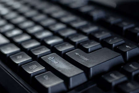 selective focus on the return key or enter key of black keyboard of desktop being pressed by a human...