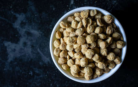 top view of a bowl full of soya bean chunks on black background