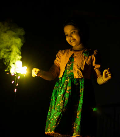 a cute indian girl child enjoying sparklers during diwali festivalの写真素材