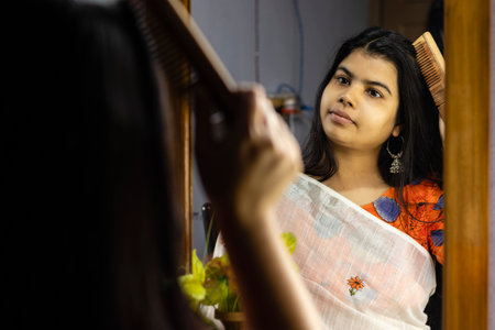 a beautiful Indian woman in white saree combing hair in front of mirror with smiling face