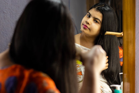 a beautiful Indian woman in white saree combing hair in front of mirror with smiling face