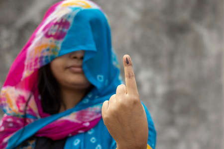 selective focus on ink-marked finger of an Indian village woman behind veil with smiling faceの写真素材