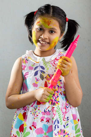 A pretty Indian girl child with colored face and water gun during Holiの写真素材