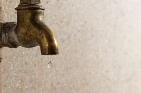 Side view of a brass metal tap, water dropping in domestic roomの写真素材