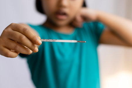 Selective focus on an analog thermometer held in hand of a child, health care conceptの写真素材