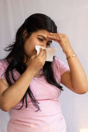 An Indian Asian woman suffering from cold and headache showing running noseの写真素材