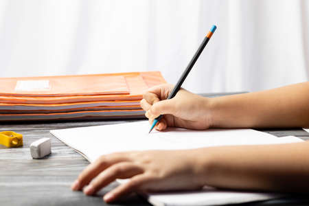 Selective focus on hand of an Indian child writing with pencil on notebook